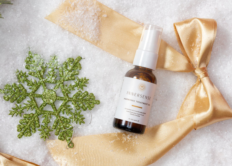 Skincare serum bottle with gold ribbon and decorative snowflake on a white background