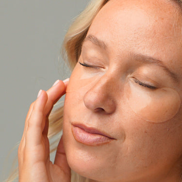 Close up of a woman applying product under her eyes.