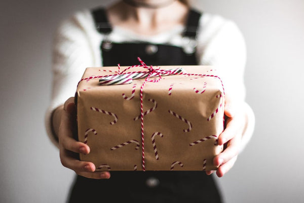 woman holding a gift in brown paper wrapping with a red string bow