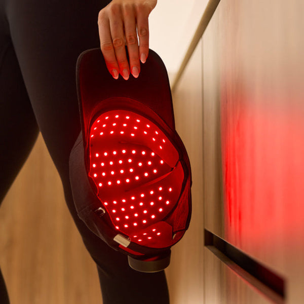 Person holding a red light cap, glowing red, reflected on nearby surface 
