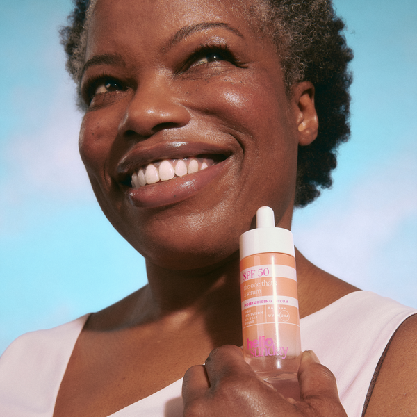 Woman holding a bottle of sunscreen with a blue gradient background