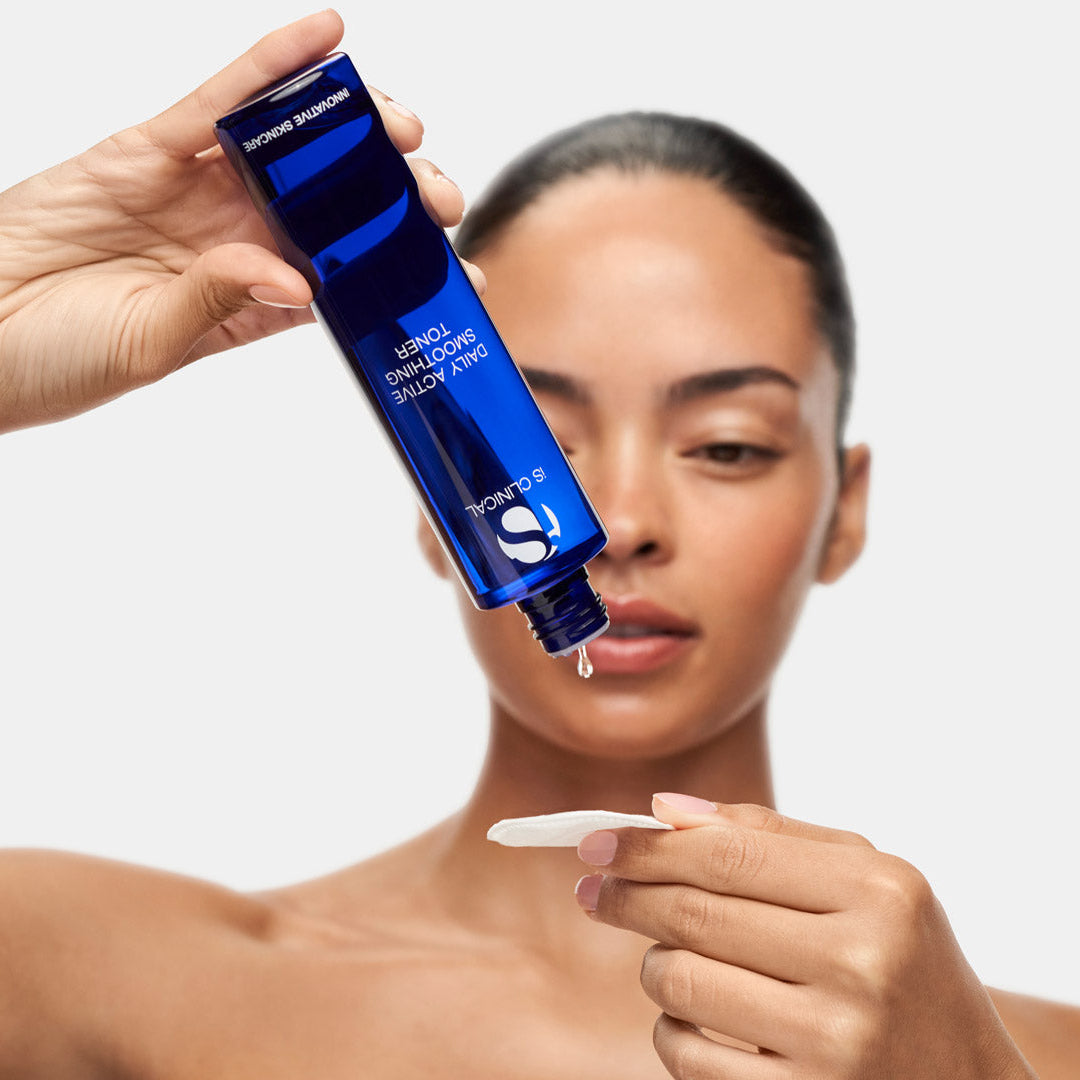 A woman holding a blue bottle of Shiseido Ultimainline Hairline Hair Building Fibro Solution and applying a drop to a swab.