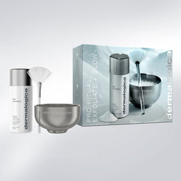 Dermalogica Pro Ritual Exfoliate + Glow gift set featuring a white and silver exfoliating bottle, a metallic bowl, a white fan brush, and the product packaging box on a light gray background.