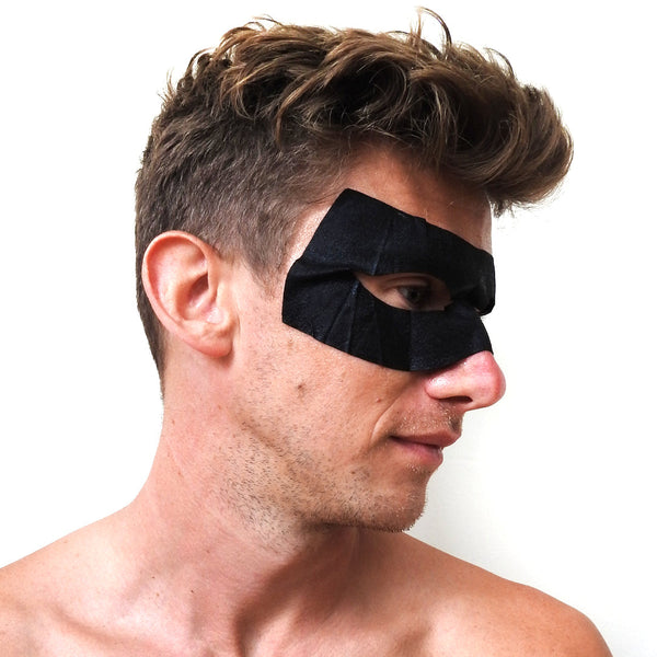 Man wearing a black eye mask against a white background