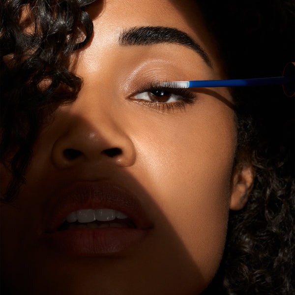 Close-up of a person applying eyeliner with a brush.