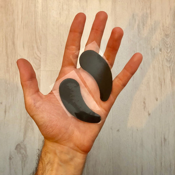 Two black shoe inserts on a person's palm against a wooden background