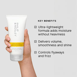 A hand holds a white tube of Phil Nigley Body Building Moisturizing Conditioner against a light gray background, with text listing key benefits on the right.