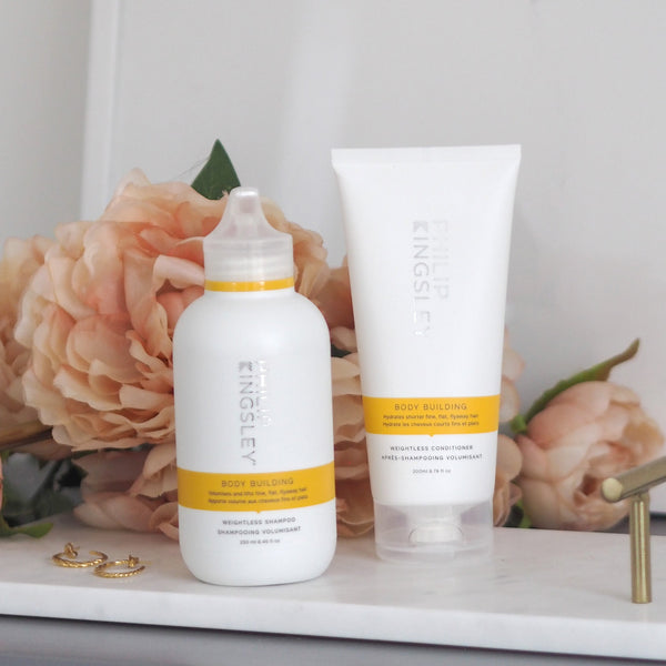 Two bottles of King & Queen skincare products on a marble surface with flowers in the background.