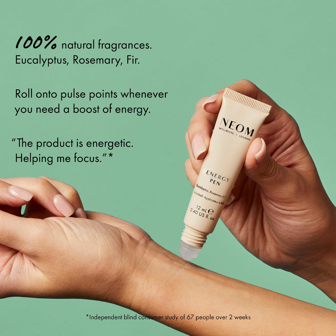 Hand holding a NEOM Energy Pen with text about natural fragrances and product benefits on a green background