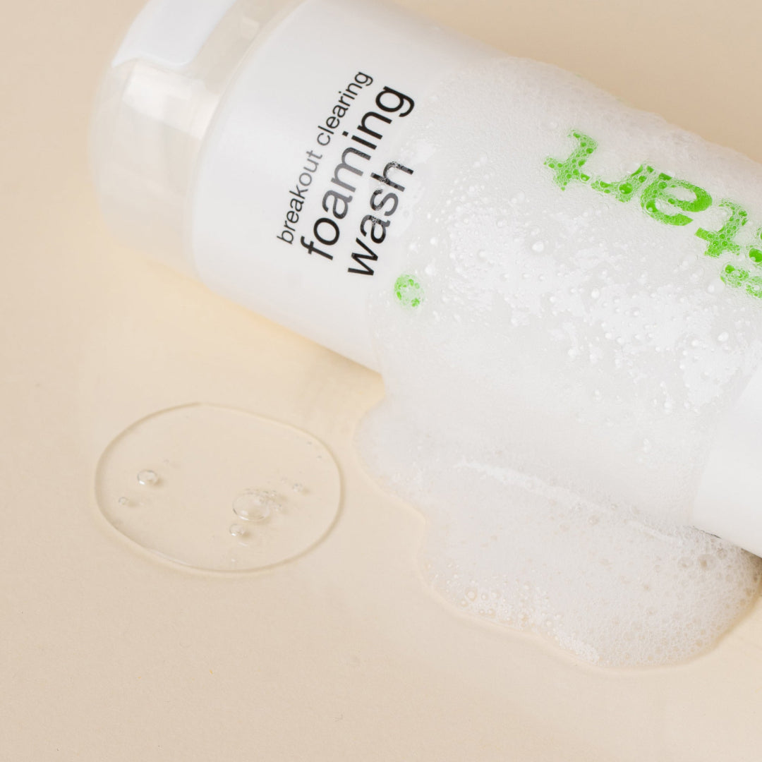 Bottle of breakout cleaning foaming wash with a beige background