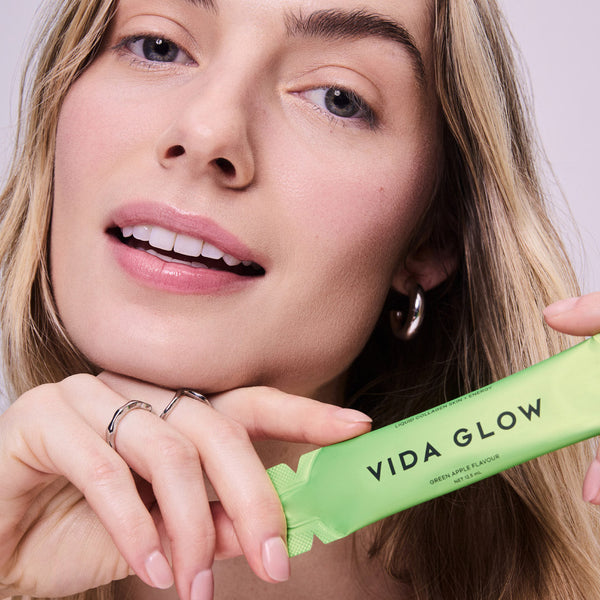 Woman holding a green Vida Glow product