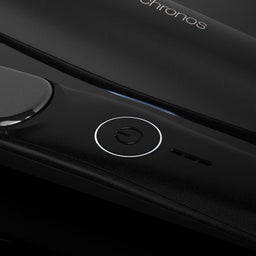 Close-up of a black electronic device with a circular power button, a glossy touch panel, and the word 'chronos' visible near the top.