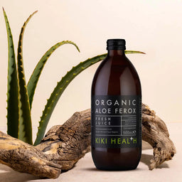 Bottle of Organic Aloe Ferox juice from Kiki Health with an aloe plant in the background.
