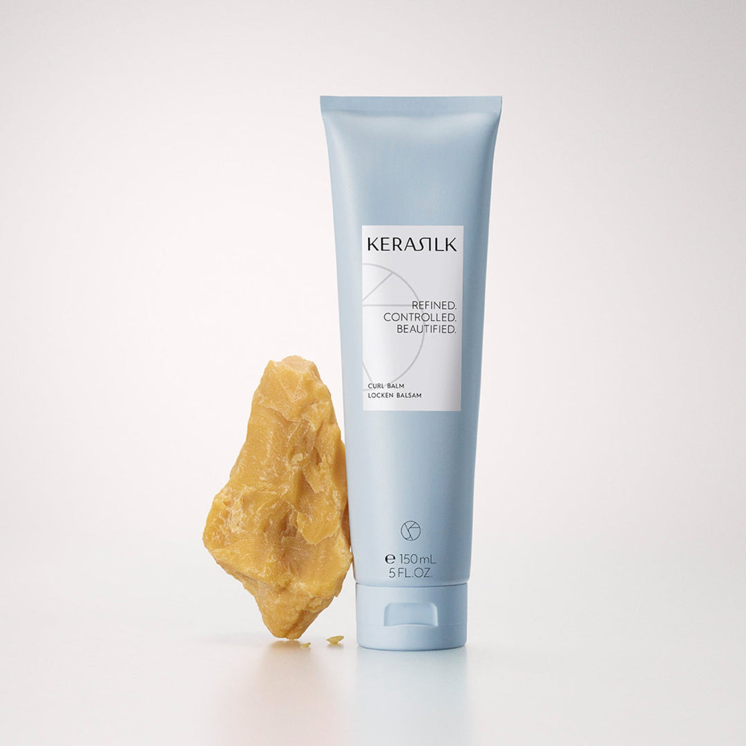 Kerasilk tube of balm with a piece of beeswax on a white background