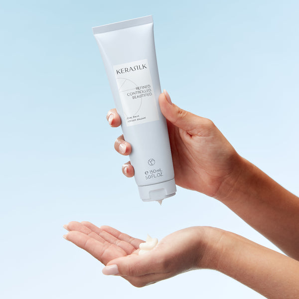 Hand holding a Kerasilk product with a light blue background