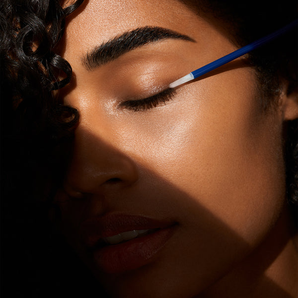 Close-up of a person applying eyeliner with a blue pencil.