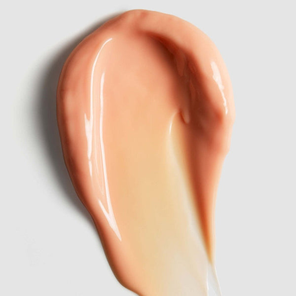 A glossy smear of peachy beige cosmetic cream or foundation on a light gray background.