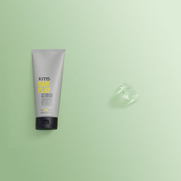 KMS Hair Play styling gel tube on a green background