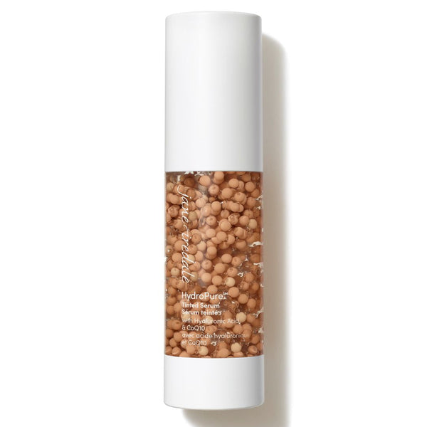 A cylindrical cosmetic bottle filled with tan-colored beads, featuring a white cap and base with the brand name 'Tetra Tidy' visible on the side, set against a plain white background with a soft shadow.