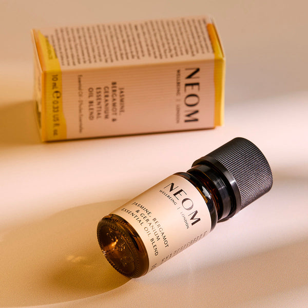 NEOM essential oil bottle and box on a beige background