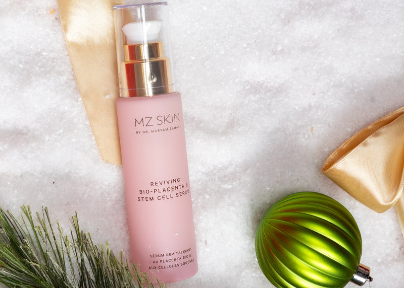 Pink skincare serum bottle with gold cap on a snowy background with Christmas decorations
