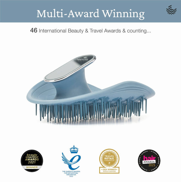 A light blue detangling brush with a silver metal handle accent, shown on a white background with award badges and text reading 'Multi-Award Winning' and '46 International Beauty & Travel Awards & counting.