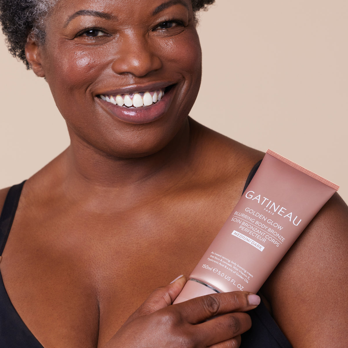 Woman holding a Gatineau product against a beige background