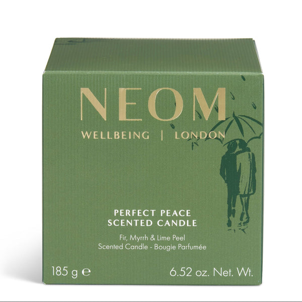 A square green box of NEOM Wellbeing London 'Perfect Peace' scented candle, featuring gold lettering and a dark green silhouette of a couple under an umbrella, on a white background.