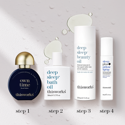 Four skincare products from thisworks are arranged in a row on a light textured background with water droplets and labeled steps 1 through 4. The products include a dark blue perfume bottle with a gold cap ('own time' Eau de Parfum), a white bath oil bottle, a tall white beauty oil tube, and a white pillow spray bottle.