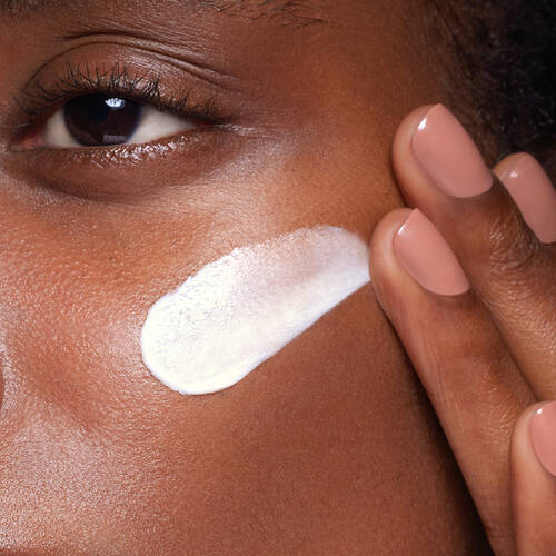 a woman applying SkinCeuticals Daily Moisture to her cheek 
