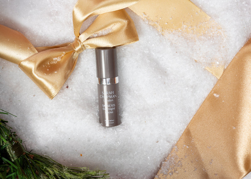 Skincare serum bottle with gold bow on a snowy background