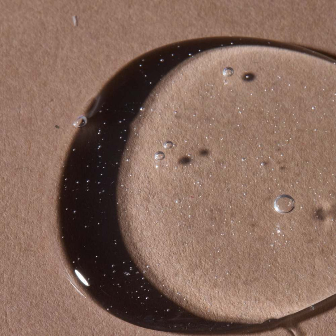 Close-up of a droplet of dark liquid on a beige surface
