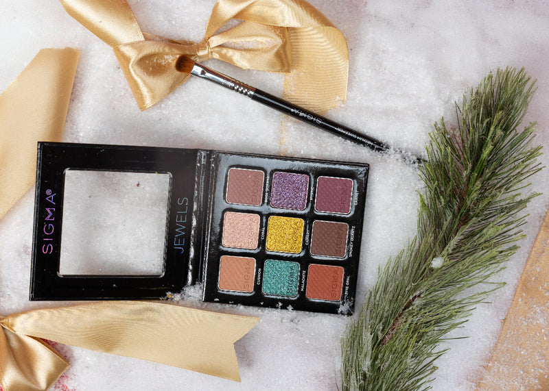 Sigma Beauty eyeshadow palette with a gold bow and greenery on a white background