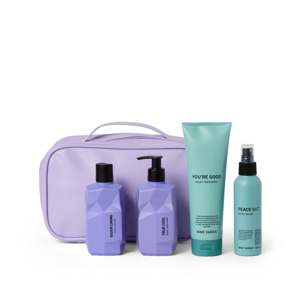 A hair care set from Nine Years Old featuring a lavender zippered pouch, two purple bottles, a mint green tube, and a mint green spray bottle, arranged on a white background.