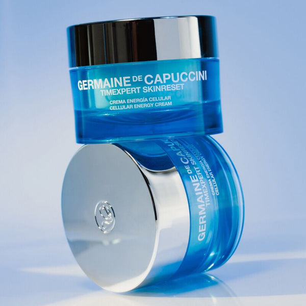 Two jars of Germaine de Capuccini Timexpert Skinreset cellular energy cream in a blue and silver color scheme, set against a light blue gradient background.