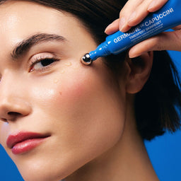 Person applying a skincare product to their face with a blue bottle labeled 'Germaine de Capuccini'.