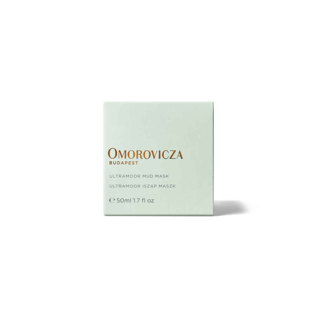 A square, pale mint green box of Omorovicza Budapest Ultramood Mud Mask, featuring gold and black text, centered on a clean white background with a soft shadow.