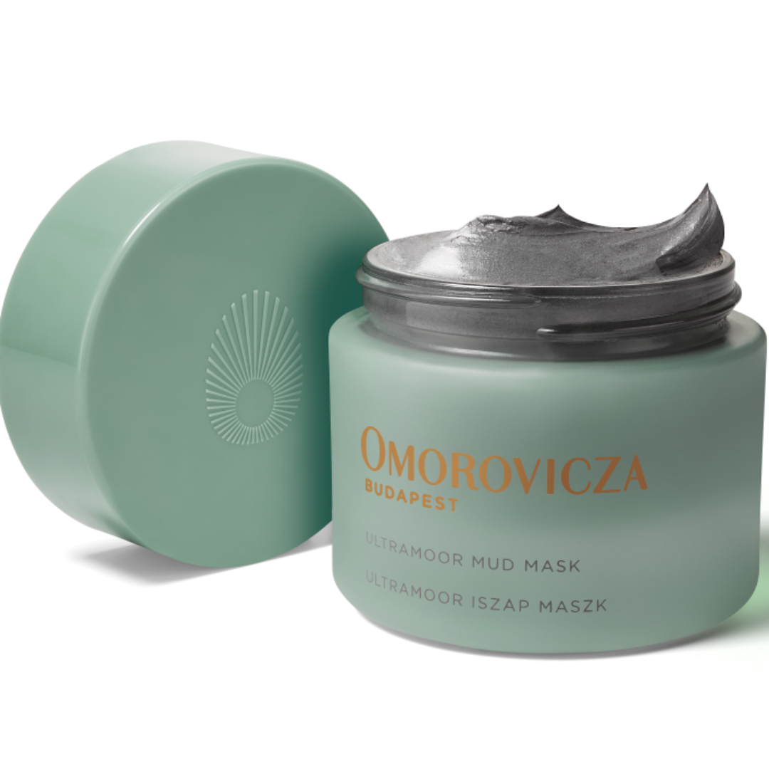 A jar of Omorovicza Budapest Ultra-Hydro Mud Mask with its lid off, showing the gray mask cream inside, on a white background.