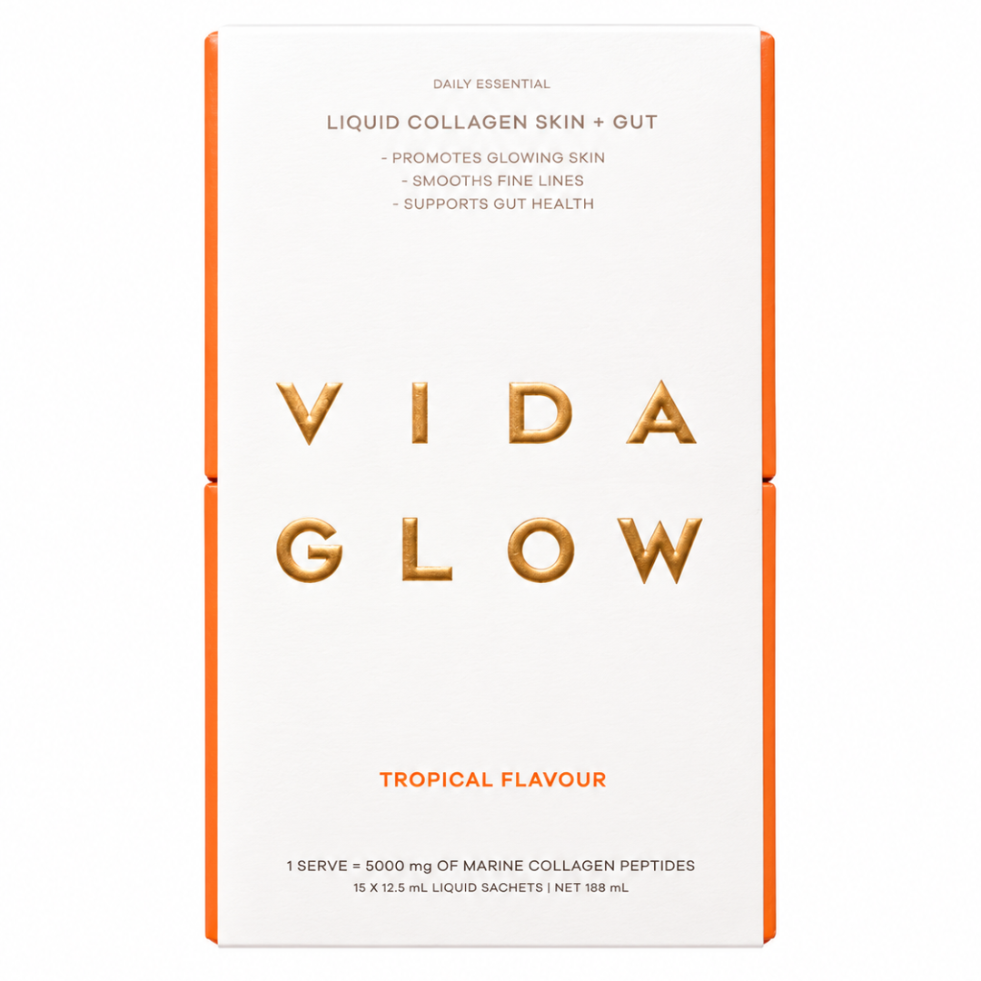 A tall rectangular box of VIDA GLOW Liquid Collagen Skin + Gut in Tropical Flavour, featuring a white front with gold foil lettering and orange side borders on a white background.