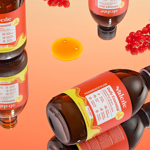 Bottles of Valenol with red berries and honey on an orange background