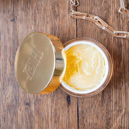 Open jar of of Emma Hardie Vit C Brilliance Cleansing balm showing product texture on a wooden surface
