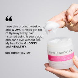 Hand holding a Philip Kingsley hair product with a customer review quote on a gray background