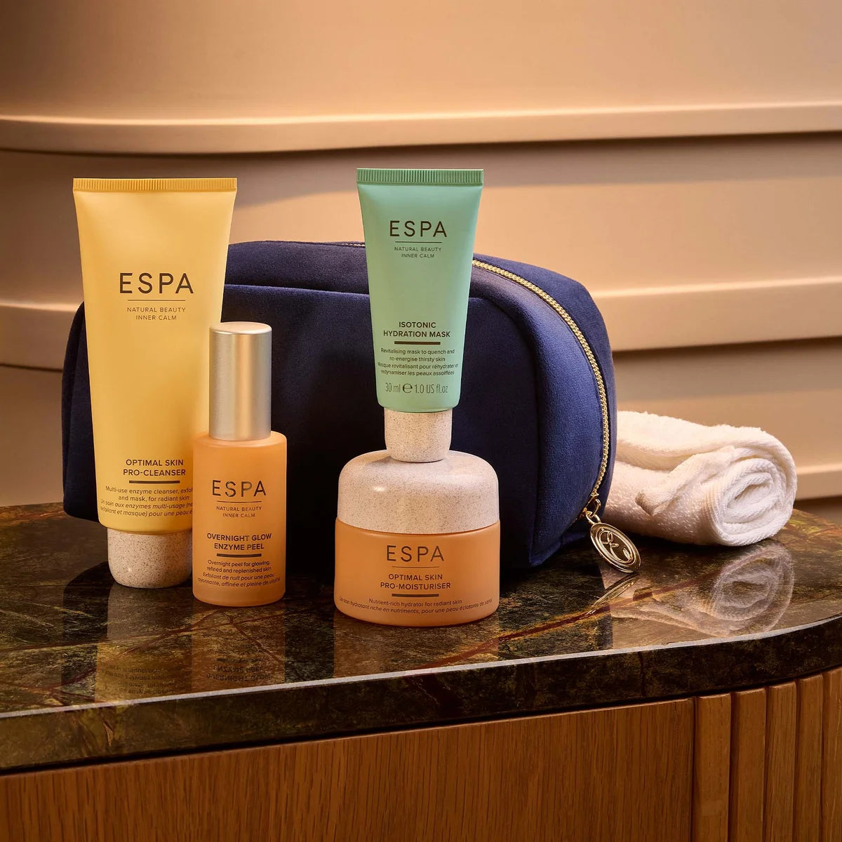 ESPA skincare products on a marble surface with a blue pouch and towel in the background.