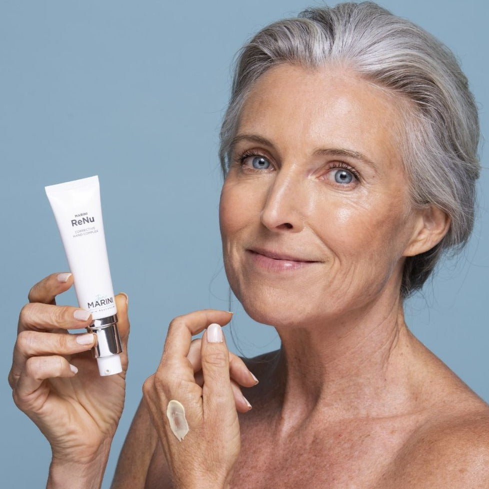 a model holding a tube of the hand complex to her face and hands