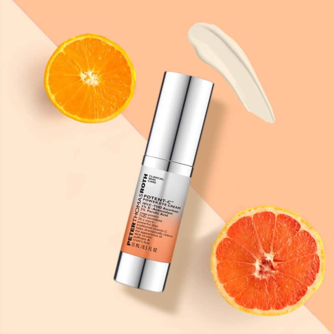 Peter Thomas Roth Potent-C Power Eye Cream 15ml bottle next to two orange slices and a smudge of texture