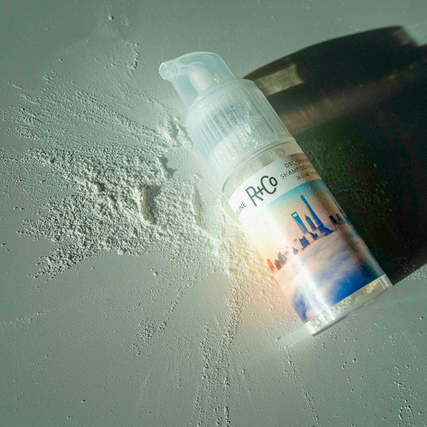 a bottle of R+Co Skyline Volume Powder with the powder surrounding the bottle